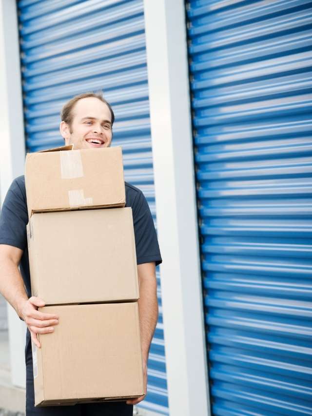 A man holding boxes at a self storage facility.