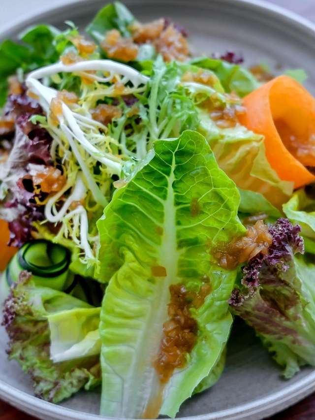 A salad with lettuce, carrots and oranges on a plate.